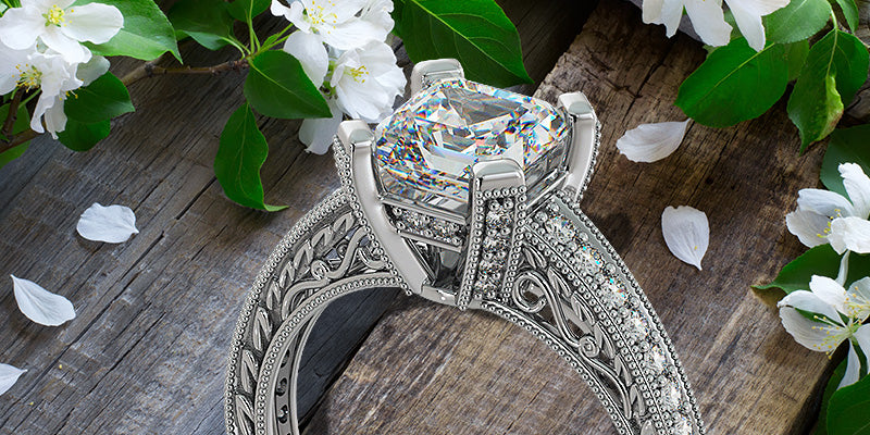 Elegant diamond ring with intricate design on a wooden surface with flowers